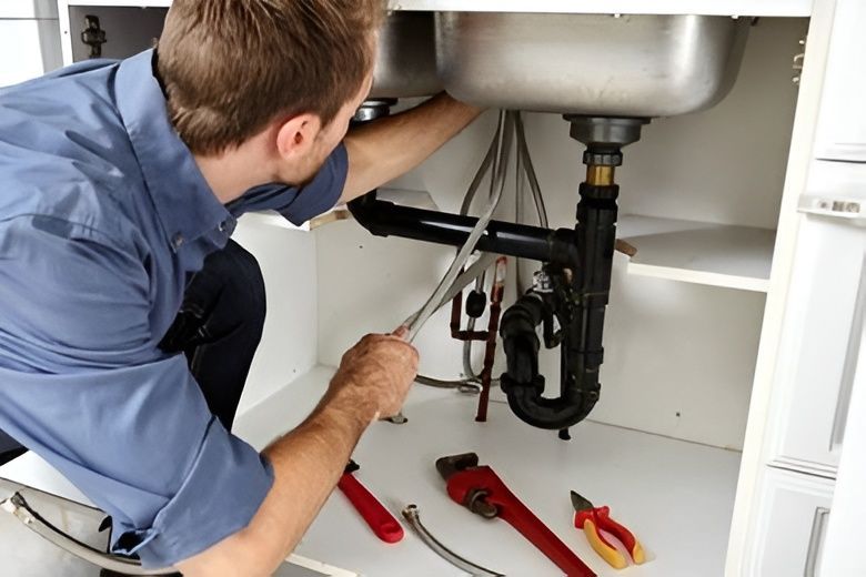 Plumber in Blue Shirt Repairs a Sink's Plumbing Using Tools — David Lewis Solahart in Alstonville, NSW