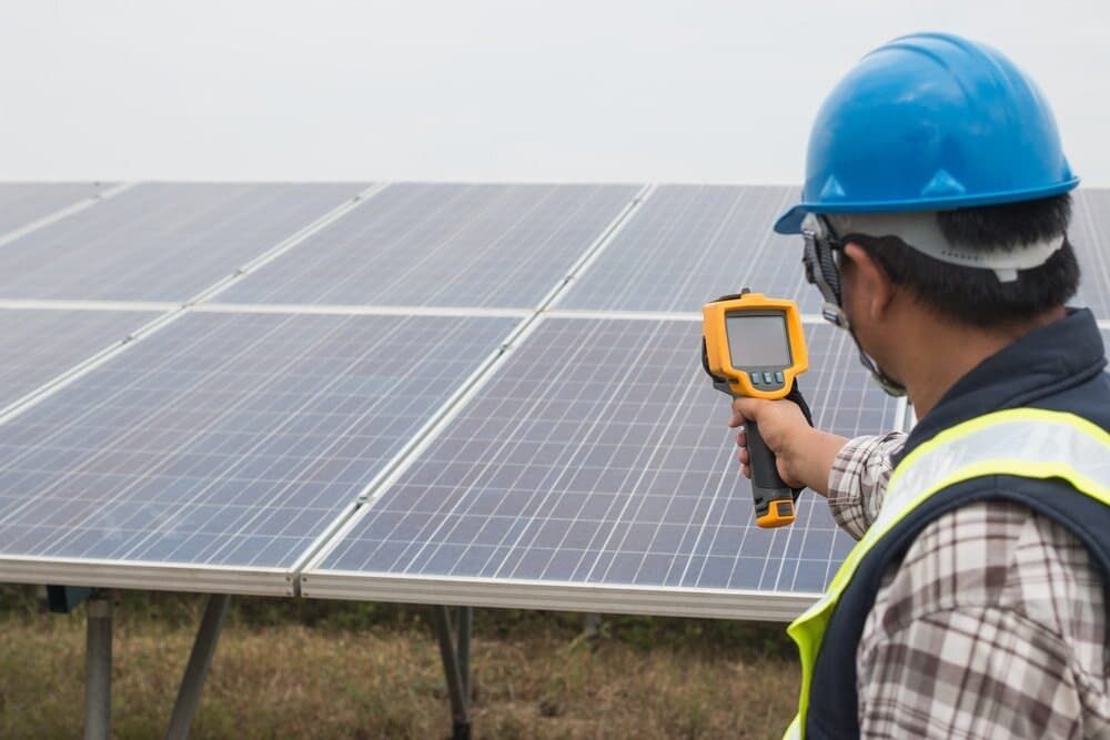 A Man Is Holding A Thermometer In Front Of A Solar Panel — David Lewis Solahart in Ocean Shores, NSW