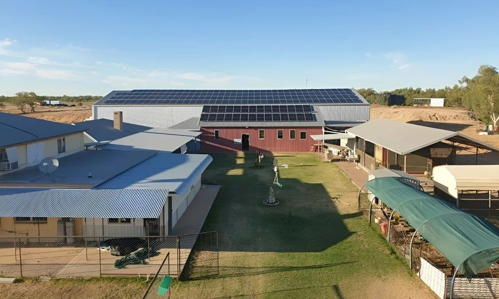 Aerial view of a rural property with multiple sheds, solar panels and a central courtyard lawn