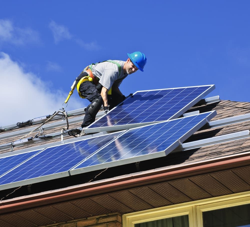 A Man Is Installing Solar Panels On The Roof Of A House — David Lewis Solahart in Evans Head, NSW