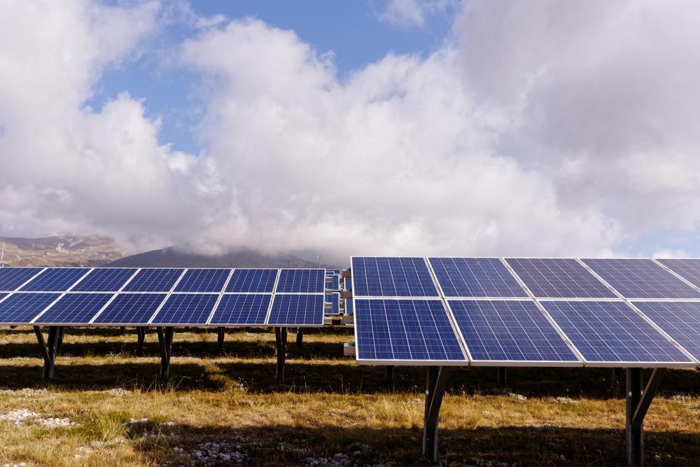 A Row Of Solar Panels In A Field With Mountains In The Background — David Lewis Solahart in Goonellabah, NSW