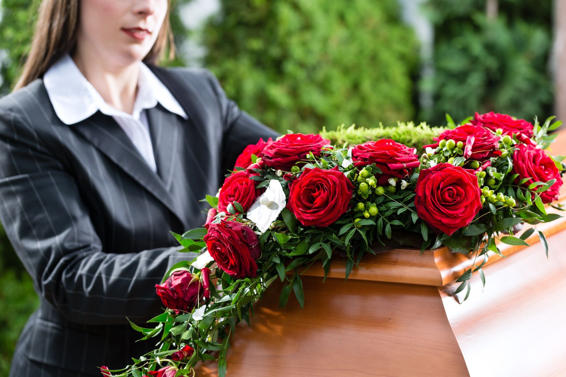 A man in a suit is sitting at a coffin at a funeral.
