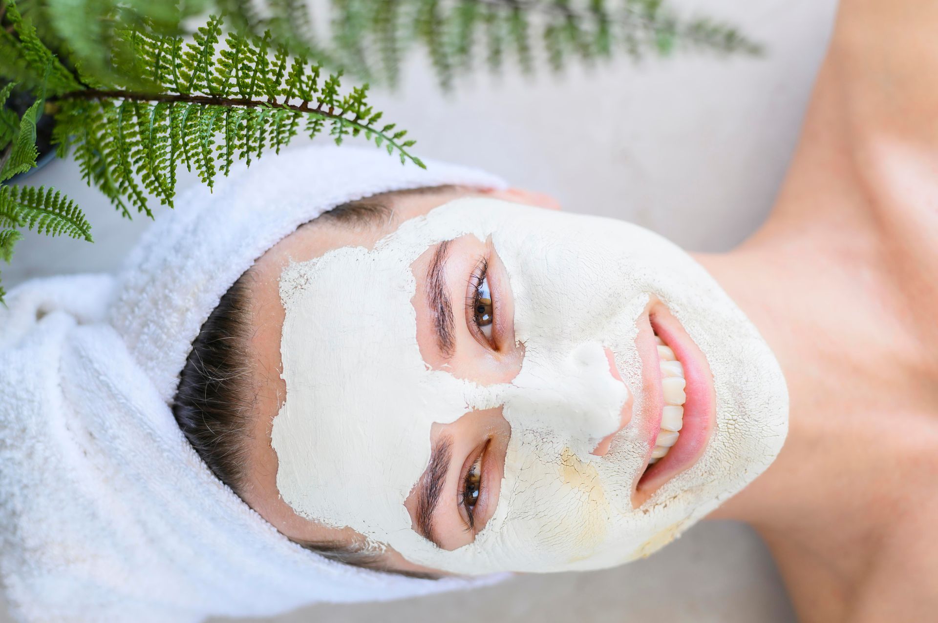 A woman is laying down with a white mask on her face.