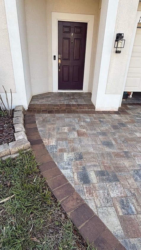 Front porch with burgundy door, stone walkway, and brick border leading to the entrance