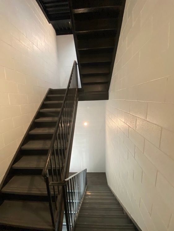 Interior stairwell with two black metal staircases and white block walls