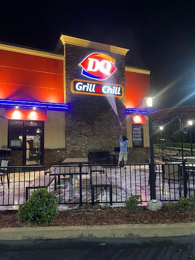 Dairy Queen Grill & Chill storefront at night with lit sign and a person standing near the entrance