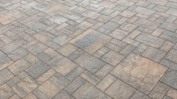 Gray and tan stone pavers arranged in a diagonal herringbone pattern
