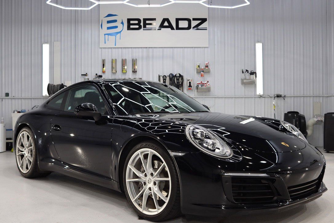 a black porsche 911 is parked in a garage .
