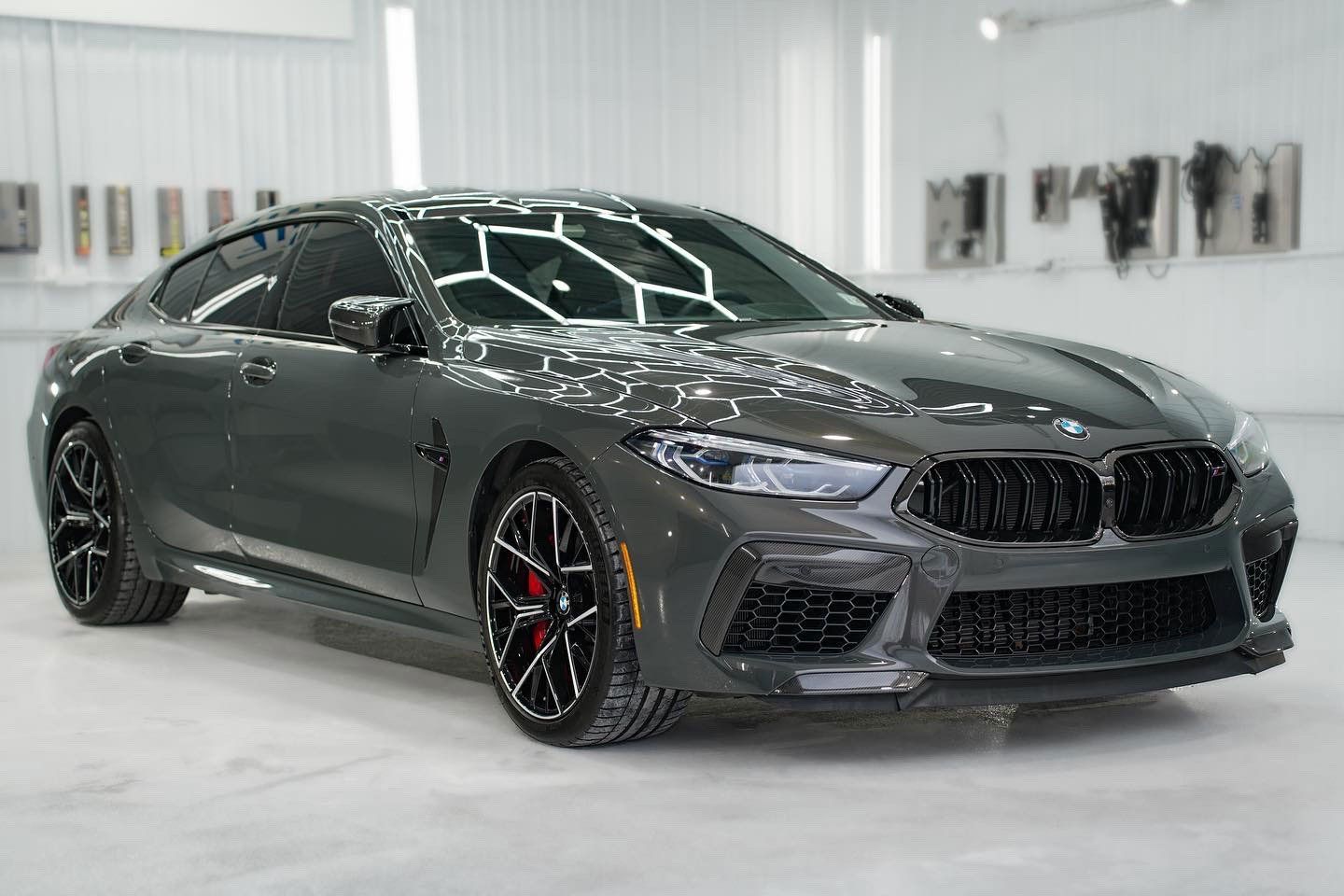 Gray BMW M8 coupe in a bright, white studio.