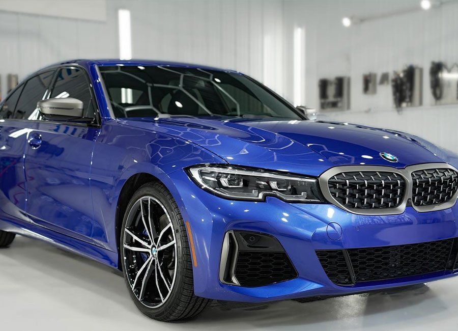 a blue bmw 3 series is parked in a showroom .