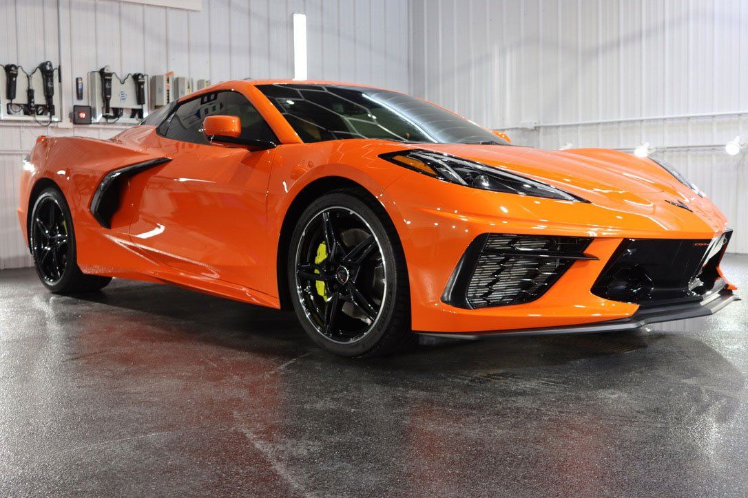 a bright orange sports car is parked in a garage .