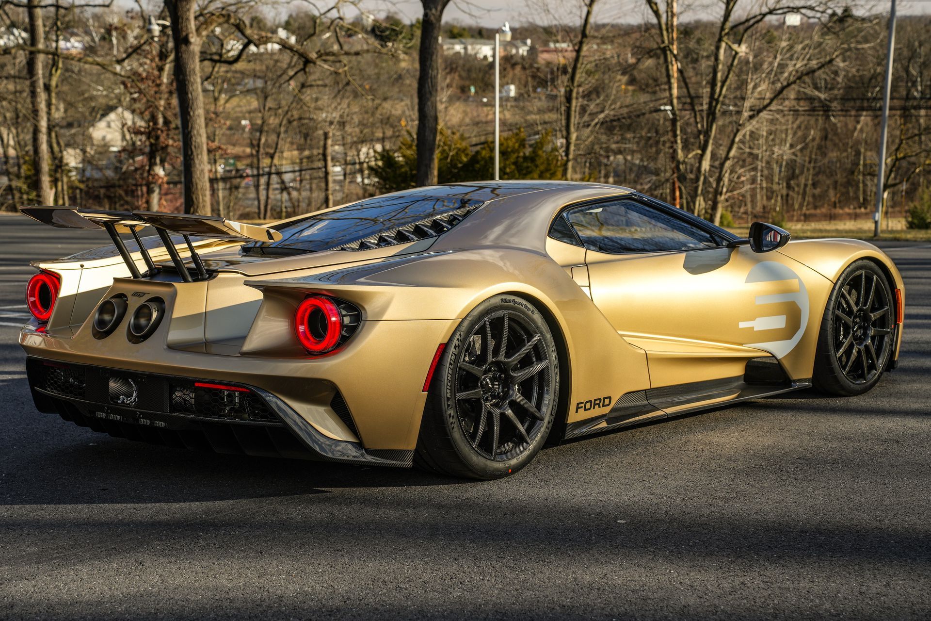 a gold ford gt is parked on the side of the road .