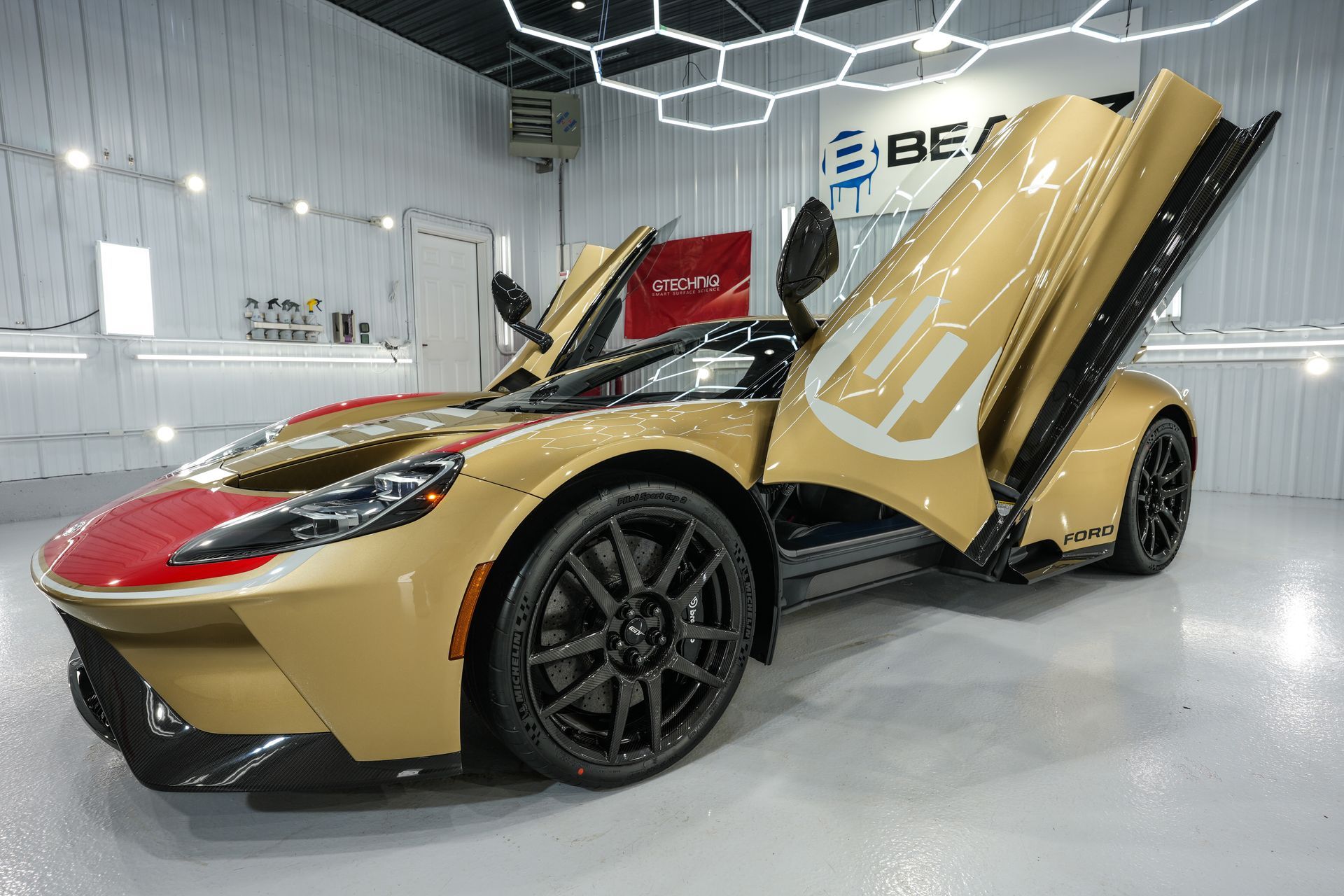 a gold and red sports car is parked in a garage with its doors open .