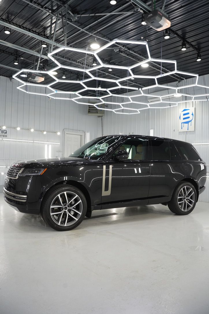 Black SUV displayed in a bright showroom under geometric ceiling lights