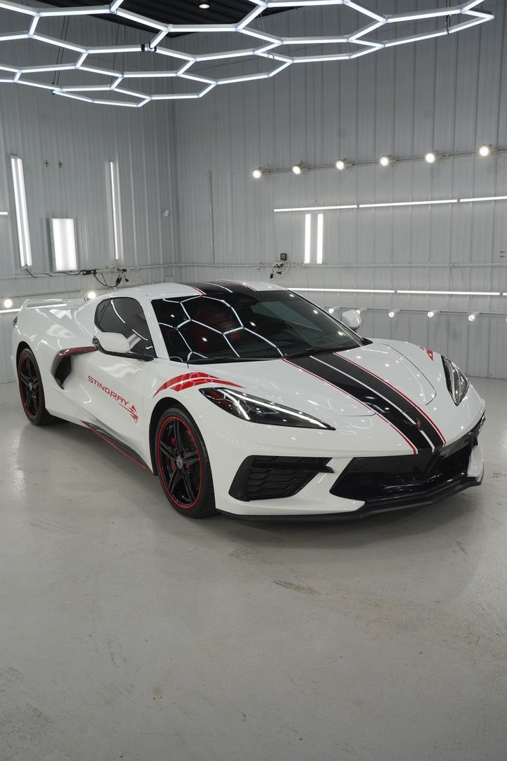 White sports car with black and red racing stripes in a bright showroom