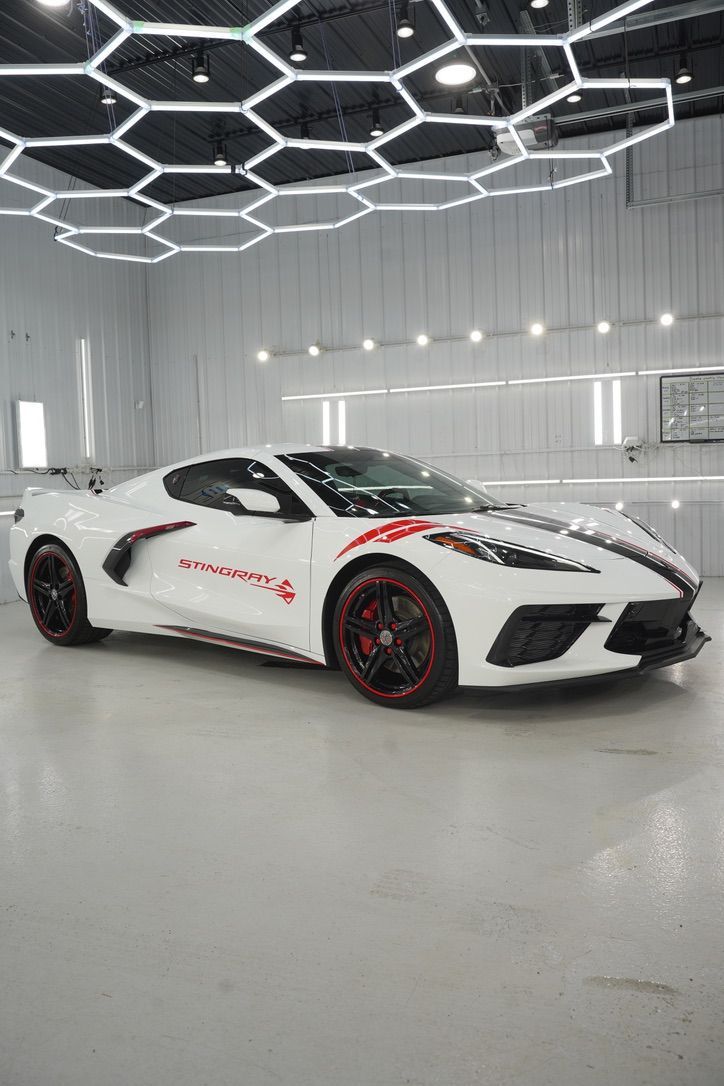 White sports car with red accents in a bright showroom under geometric ceiling lights