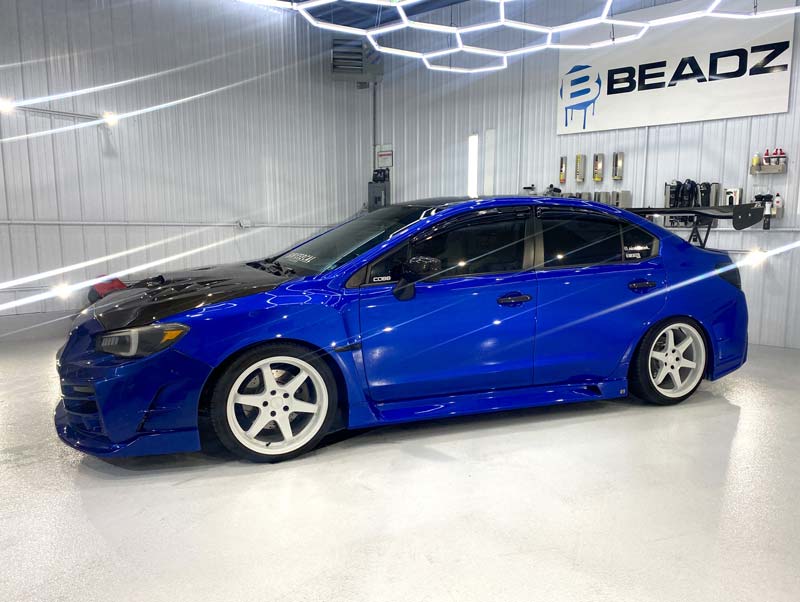 a blue subaru wrx sti is parked in a car wash .