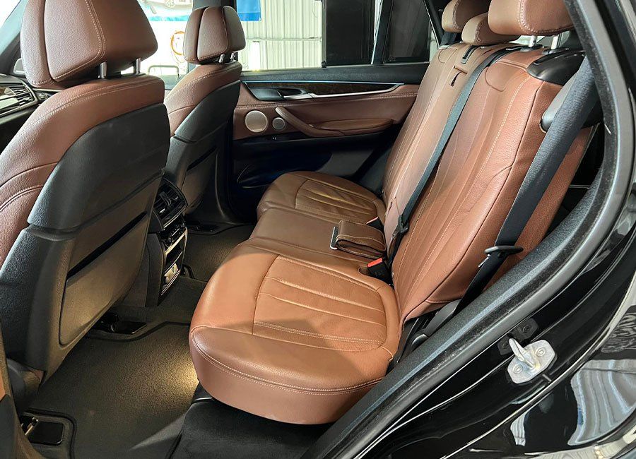 the back seat of a black bmw x5 with brown leather seats .