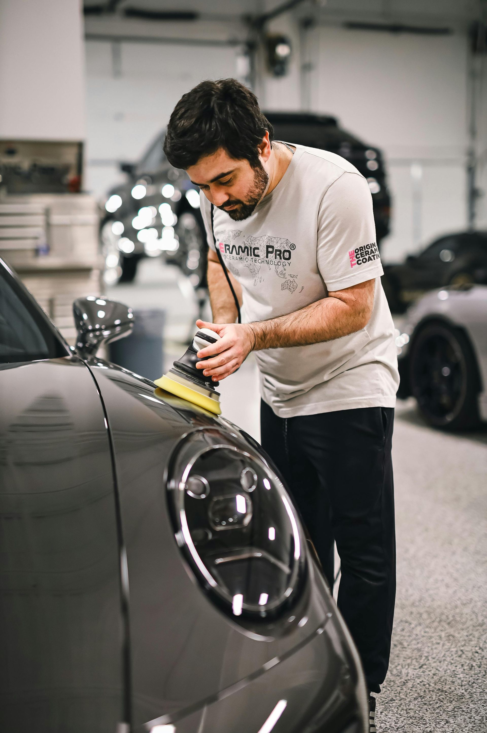 A man is polishing a car in a garage.