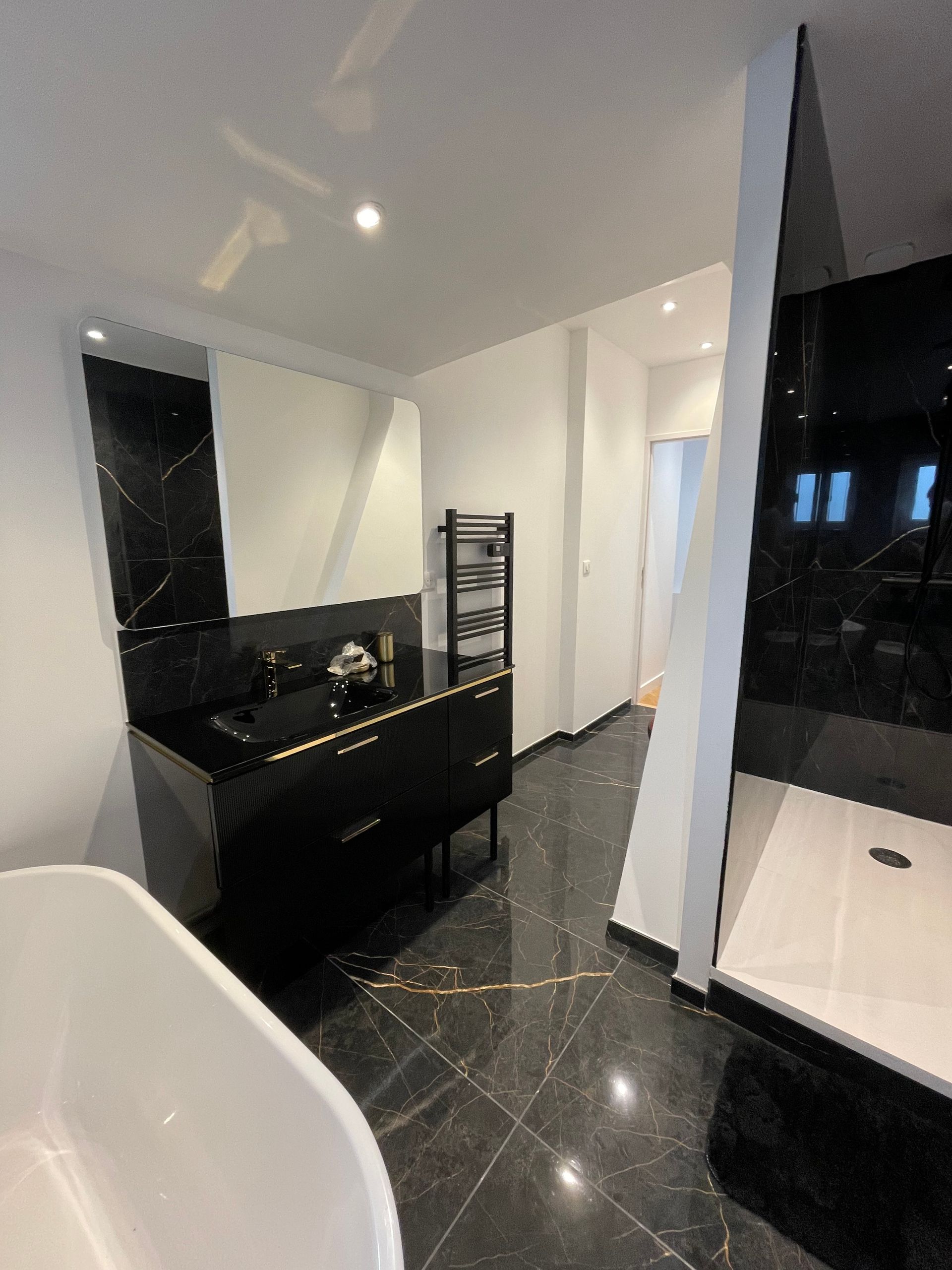 Une salle de bain avec baignoire, lavabo, miroir et douche.