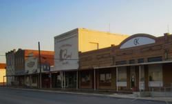 Small-town street with a row of storefronts in warm evening light
