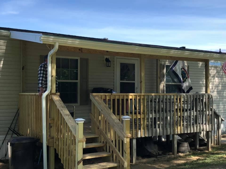 A mobile home with a wooden deck and stairs.