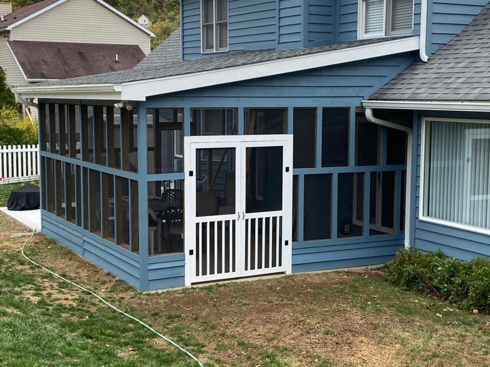 A blue house with a screened in porch attached to it.