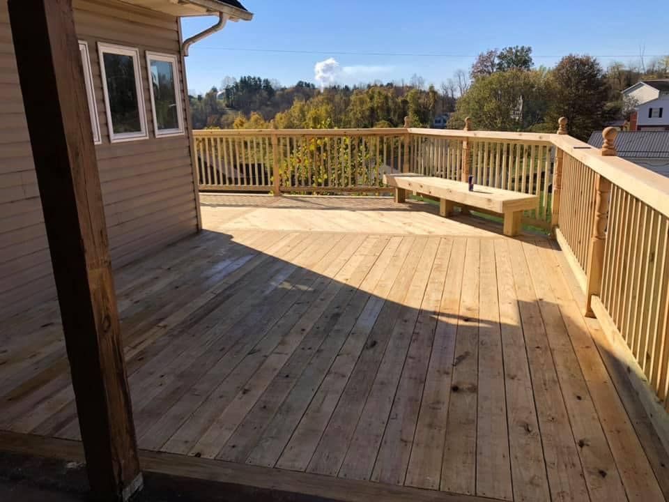 A wooden deck with a bench and railing is sitting on top of a house.