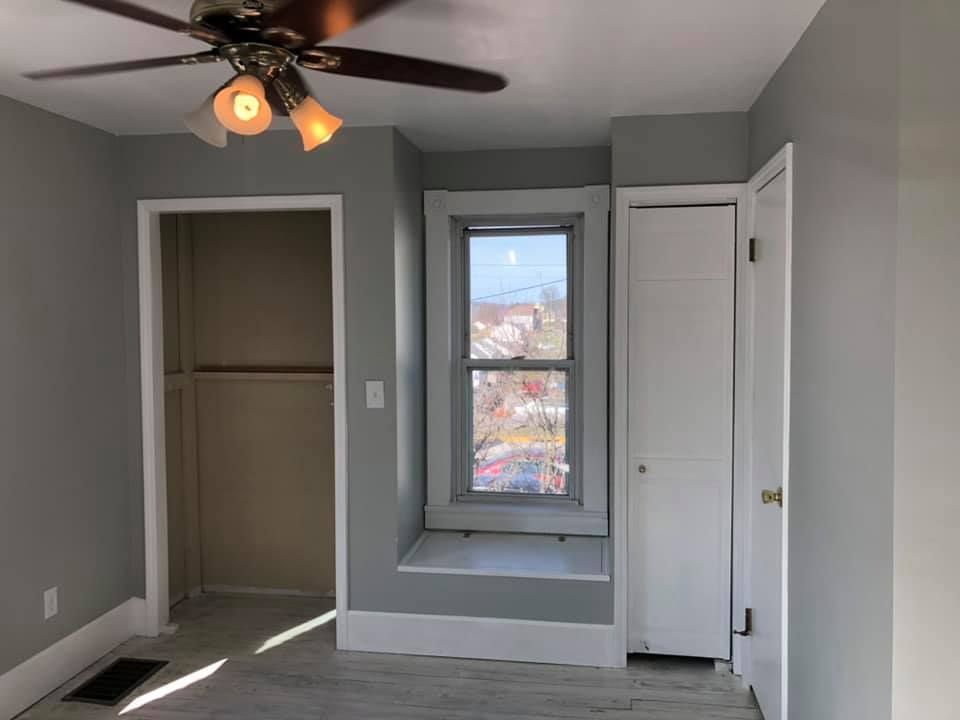 An empty bedroom with a ceiling fan and a window.