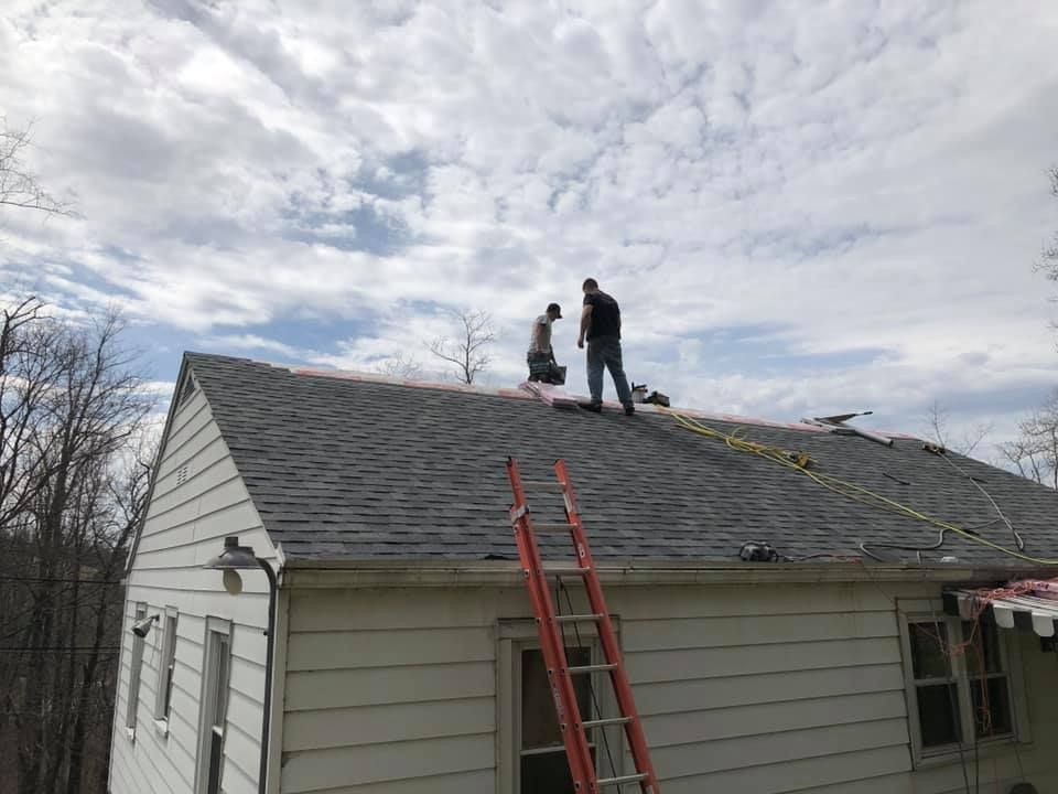 Two men are working on the roof of a house.
