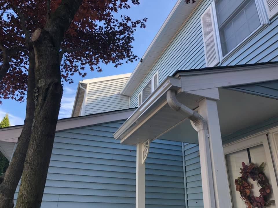 A house with a porch and a tree in front of it.
