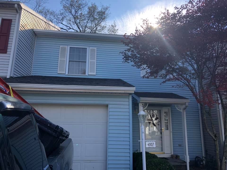 A blue house with a white garage door and a black roof.