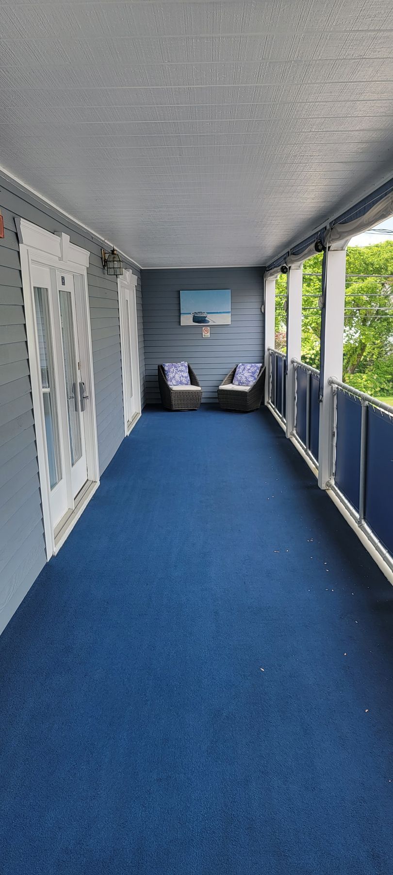 A long hallway with blue carpet and chairs in a hotel.