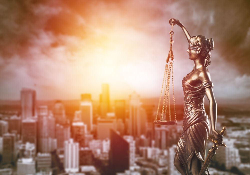 A Statue Of Justice Holding Scales Of Justice In Front Of A City Skyline — McNeilly Lawyers In Kempsey, NSW