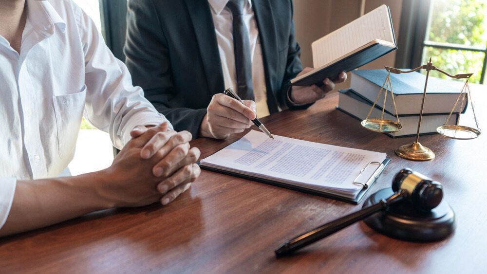 A Man Is Sitting At A Table With A Lawyer — McNeilly Lawyers In Kempsey, NSW