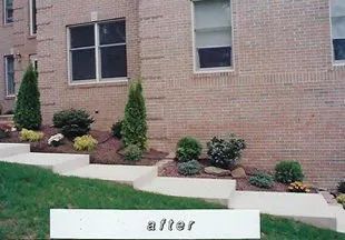 A picture of a brick house with a garden in front of it.