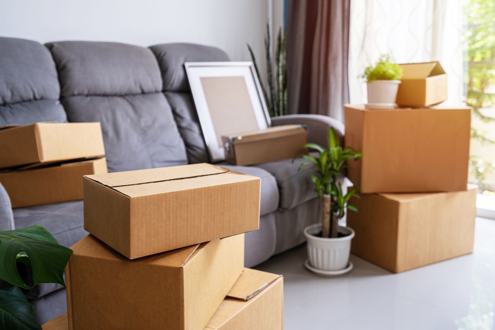 Several stacks of cardboard boxes are placed inside a living room. Several stacks of cardboard boxes are placed inside a living room.