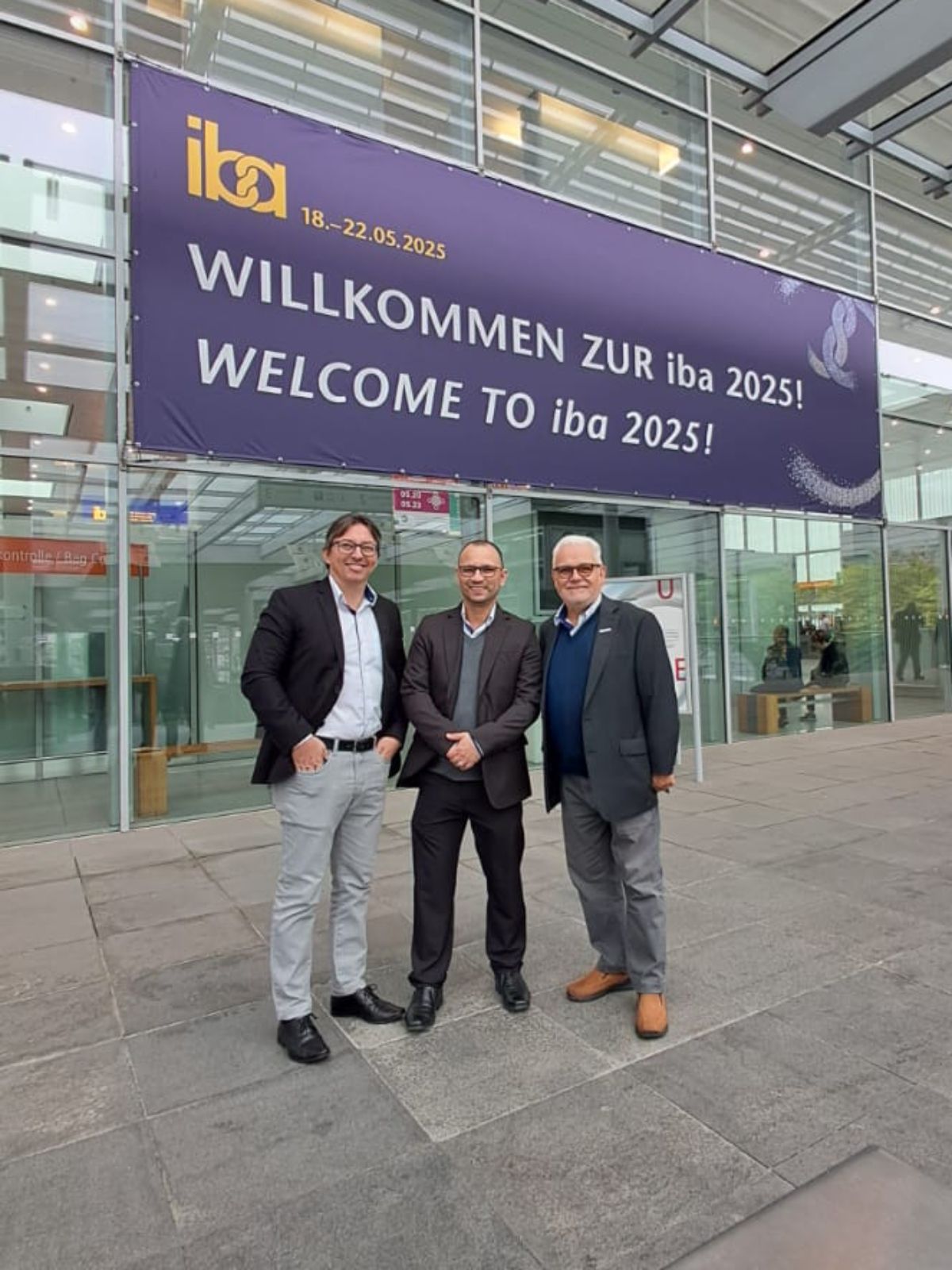 Three men standing in front of a banner reading
