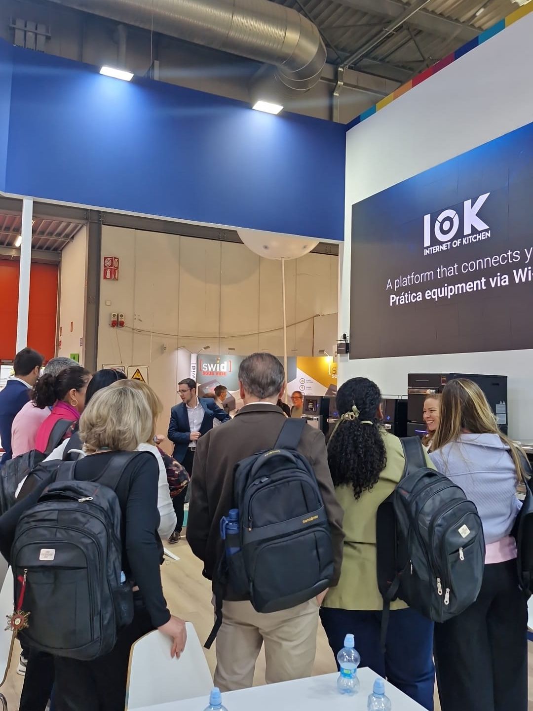 People at a trade show booth with a screen displaying 