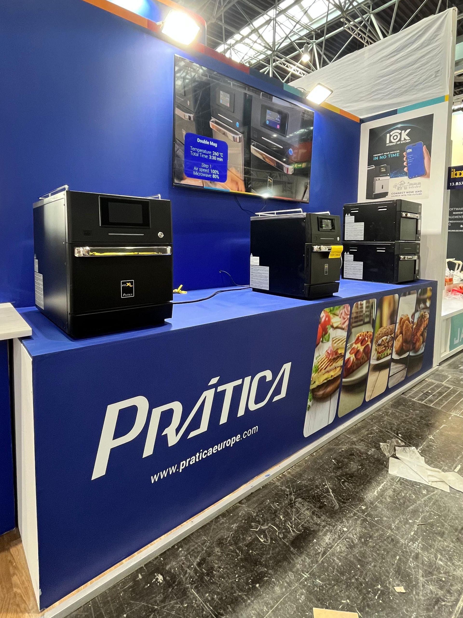 A trade show booth with black commercial ovens on a blue counter featuring the brand name