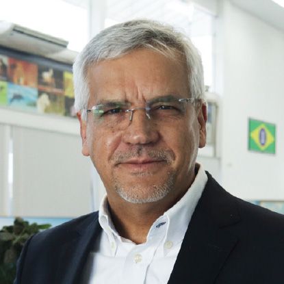 A man wearing glasses and a suit looks at the camera