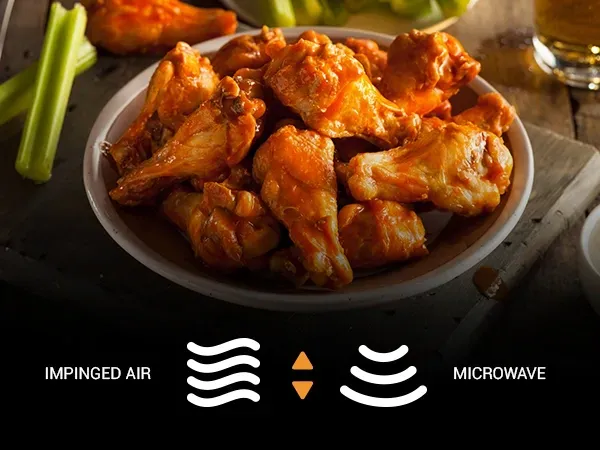 A bowl of chicken wings is sitting on a table next to celery and a glass of beer.