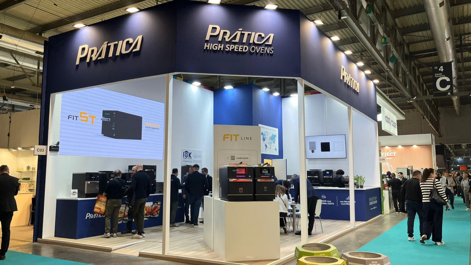 Prática trade show booth, navy and white, with products on display and people viewing.