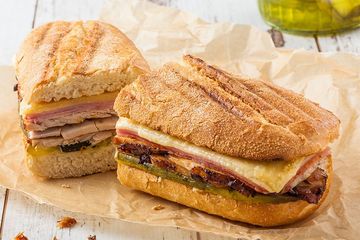 Two sandwiches are sitting on a piece of paper on a table.