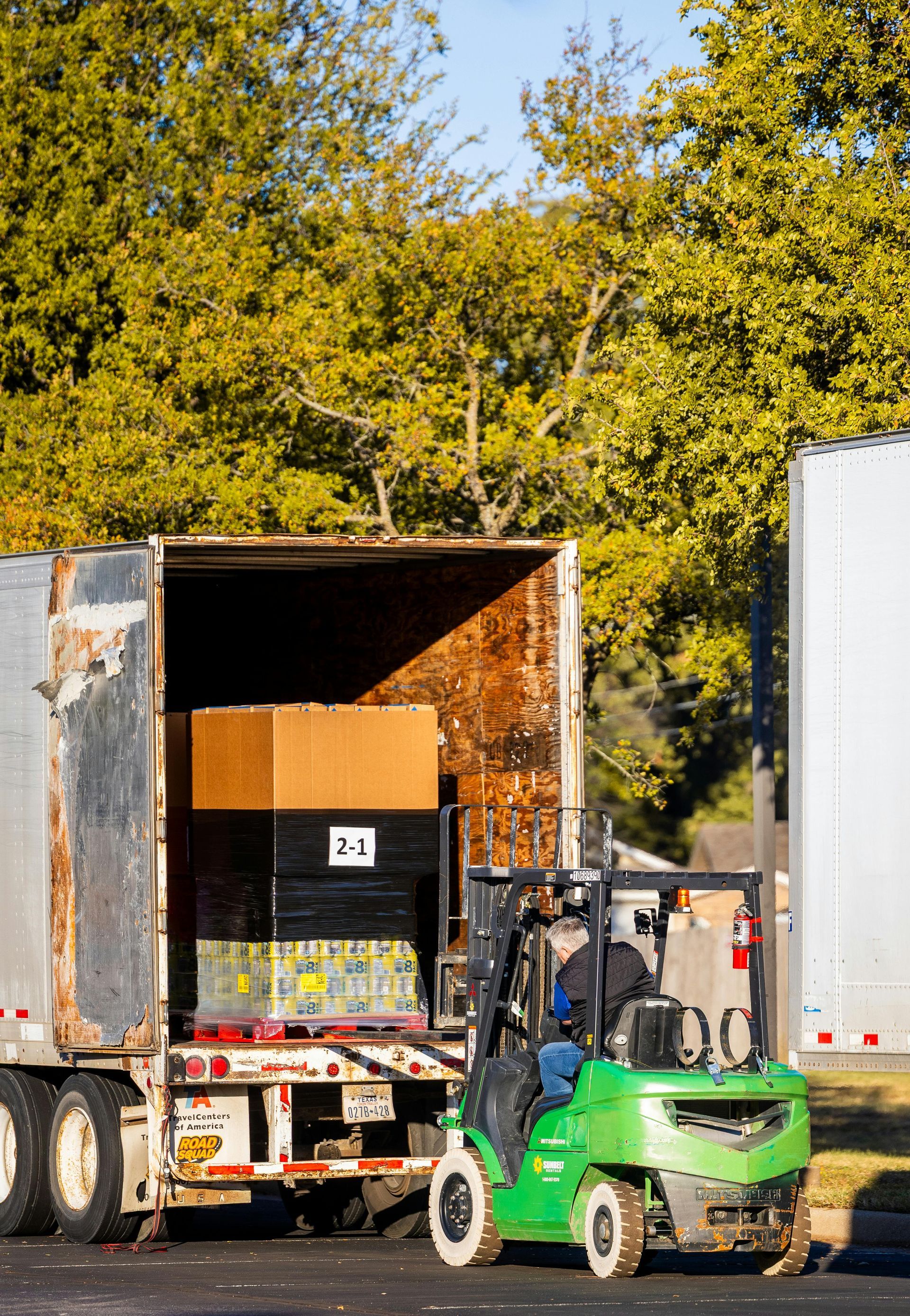 Man in hard hat loading equipment into a truck on a sunny day.