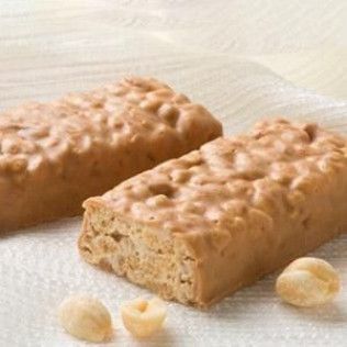 Two peanut butter bars on a plate, with a few loose peanuts.
