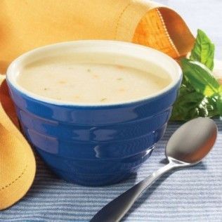 Blue bowl of creamy soup with a spoon and basil.