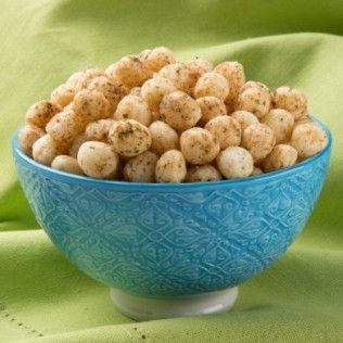 Blue bowl filled with seasoned puffed snacks on a green surface.