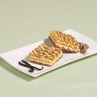 Two dessert squares drizzled with chocolate on a white plate with vanilla beans and chocolate chunks.