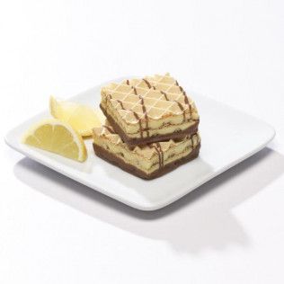 Two stacked, square wafer cookies with chocolate drizzle and lemon slices on a white plate.